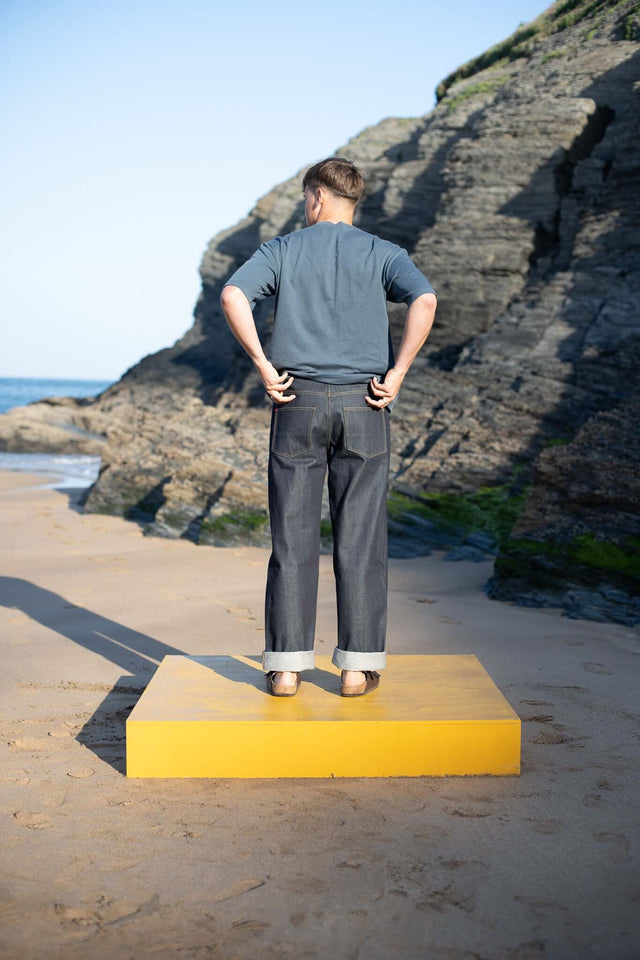 Person standing on a yellow platform with rocky cliffs and ocean in the background