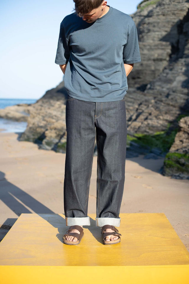 Person standing on a yellow platform with rocky landscape and ocean in the background