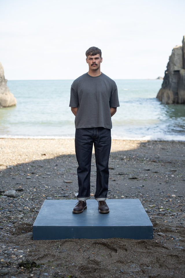 Man standing on a platform with ocean and cliffs in the background