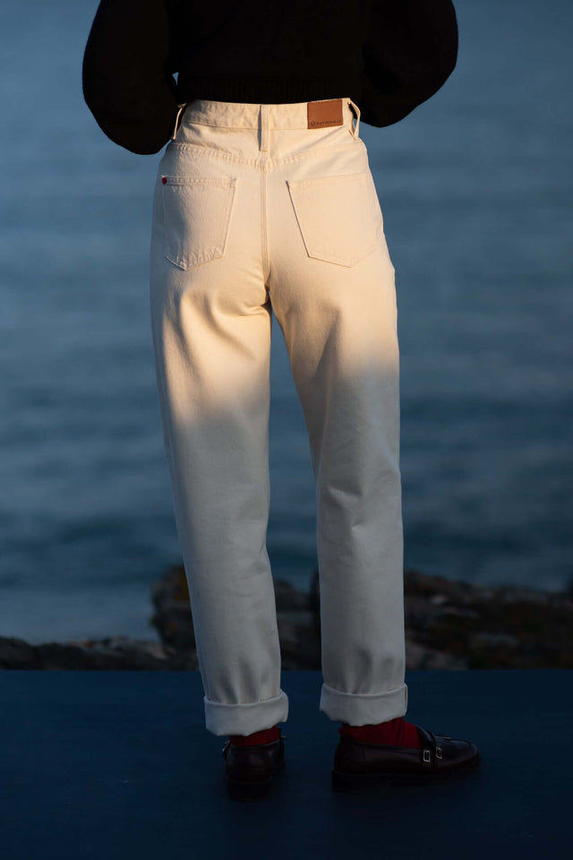 Person wearing white pants with a blurred background of water and sky